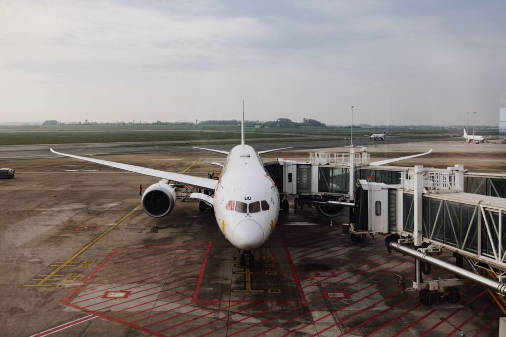 A modern jet airplane docked at an airport terminal gate, ready for boarding on a cloudy day.